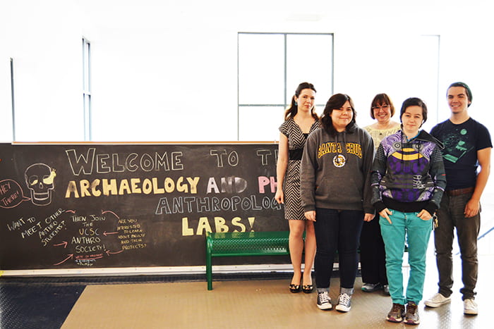 Five Monterey Bay Archaeology Archives students standing in front of chalkboard that says welcome