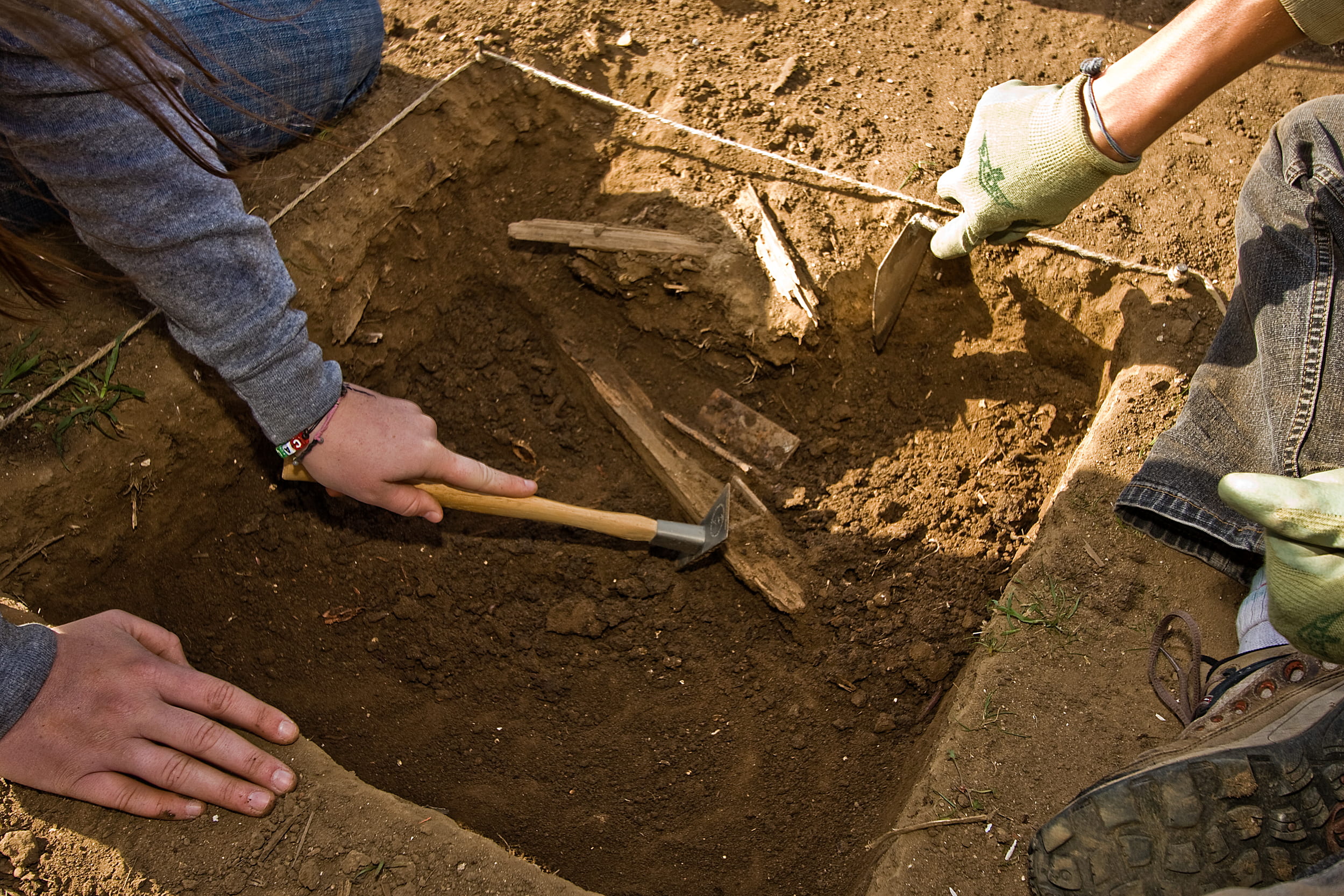 students performing an archeological dig with just hands in frame