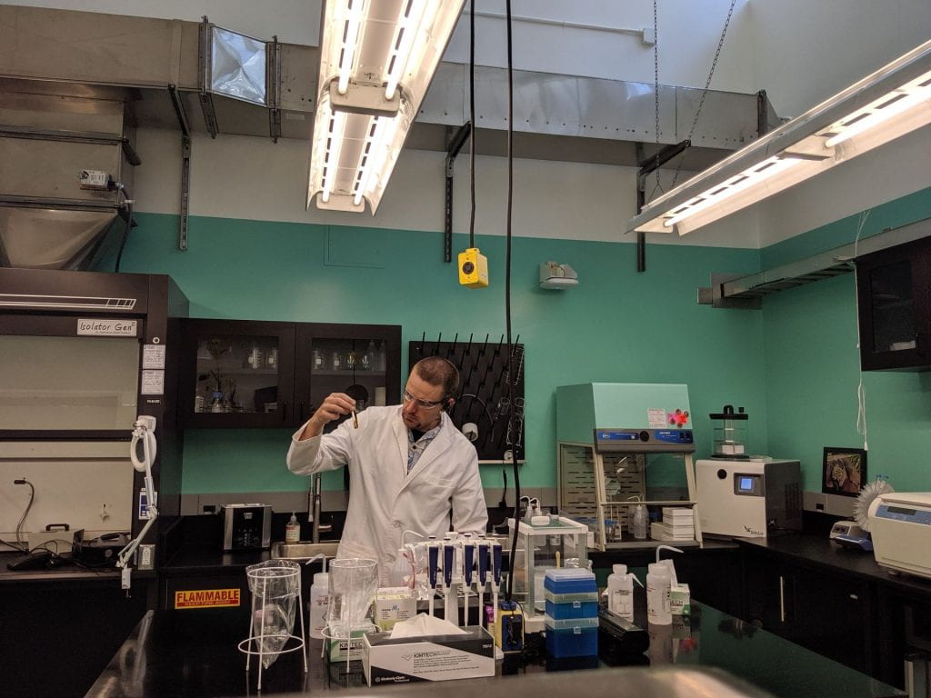 graduate student working in lab setting holding up test tube
