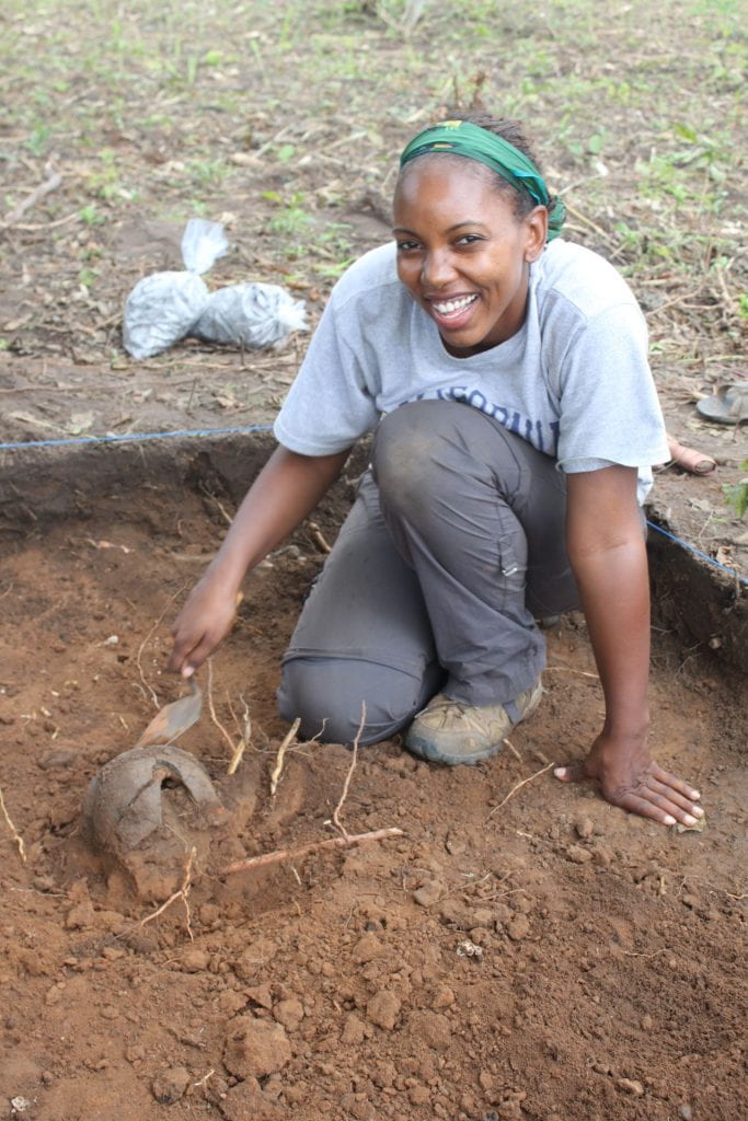 student in the field digging in a plot