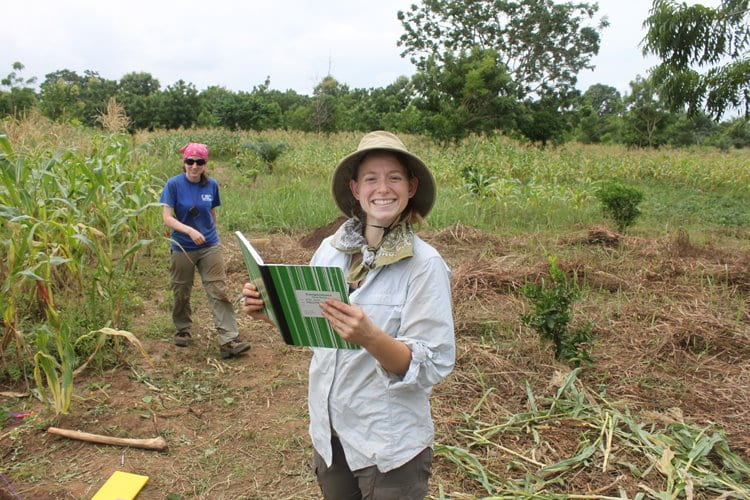 two students working in the field, one centered with a notebook in hand